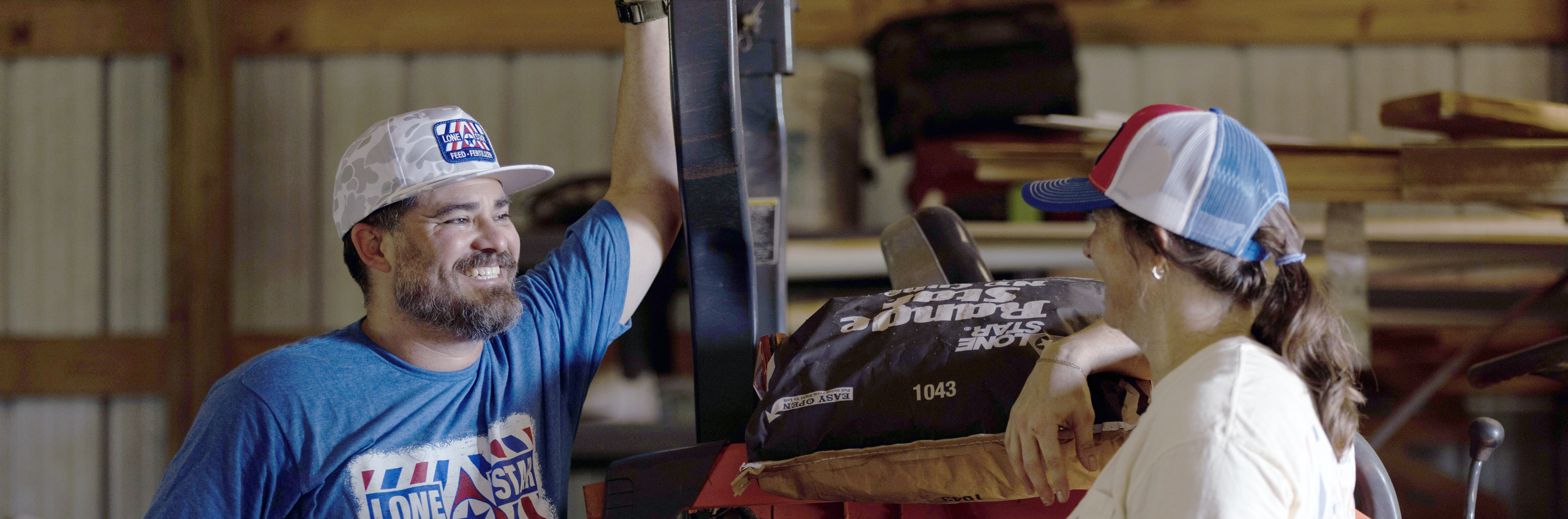 man and woman at a tractor talking wearing lone star feed apparel