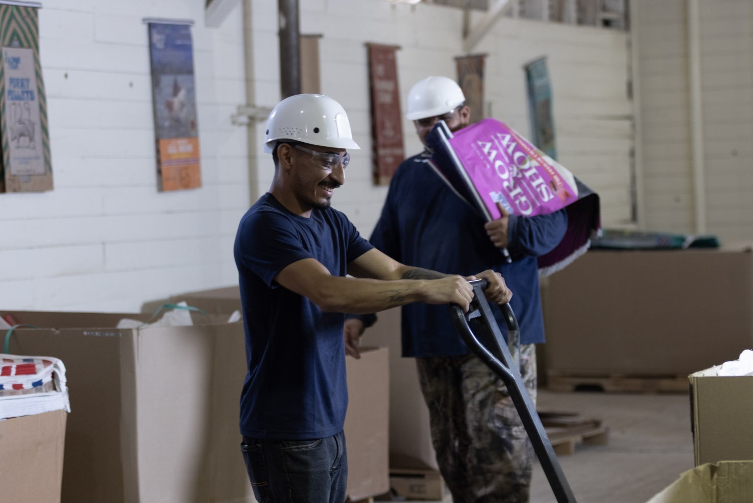man with pallet jack and man carrying empty bag