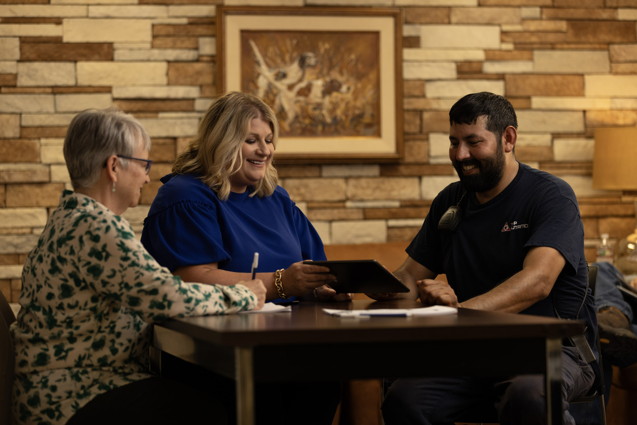 Two women and man around table looking at tablet